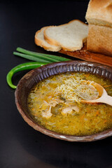 Wooden bowl with free range chicken noodle soup isolated on black, rustic setup