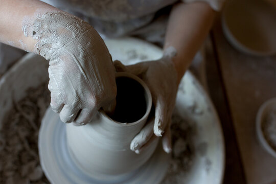 Woman making pottery on spinning wheel in her workshop