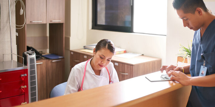 Nurse and nurse assistant working on electronic tablets