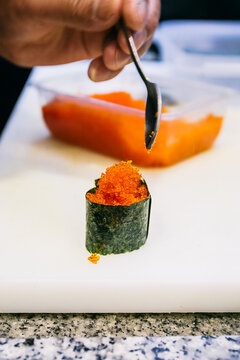 Hand of a chef placing fish roe using a spoon during a gunkan preparation 