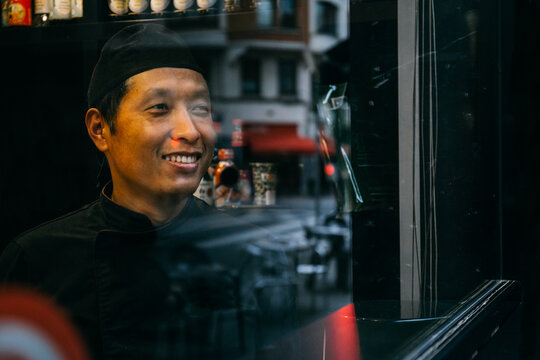 Asian chef smiling looking out the window in Bilbao, Spain