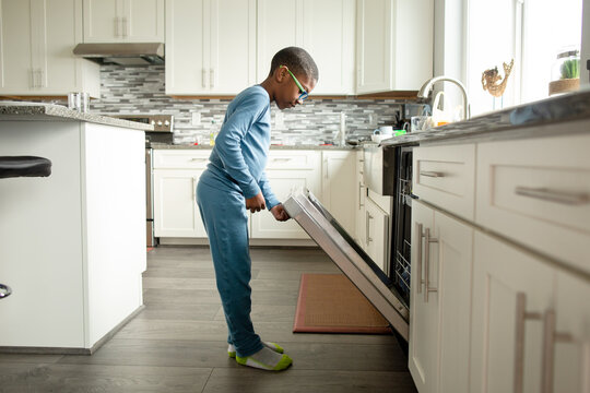 Boy opens stainless steel dishwasher