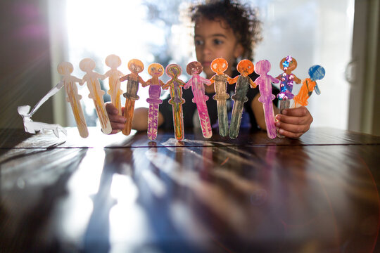 Child plays with decorated popsicle stick dancers