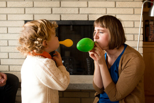 Mother And Young Son Blow Up Balloons Together