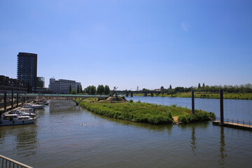 Obraz premium Venlo, Netherlands - June 9. 2021: View over river Maas on skyline of dutch city with harbor and boats in summer