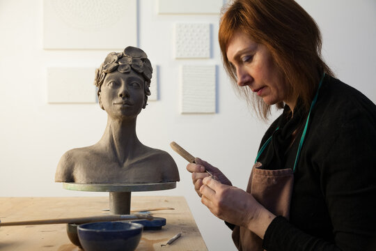 side view of an potter shaping details of a clay statue