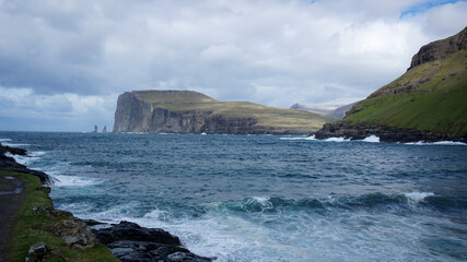 Risin and Kellingin rocks as seen from Tjornuvik bay with waves hitting the shore on Streymoy on the Faroe Islands, Denmark, Europe