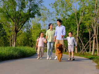 Happy family of four walking dogs in the park