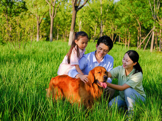 Happy family of three and pet dog playing in the park
