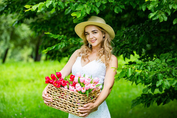 Fototapeta premium Beautiful woman resting in park sitting on a picnic blanket with fruits and wine. 