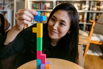 female asian woman playing with a wooden puzzle tetris style