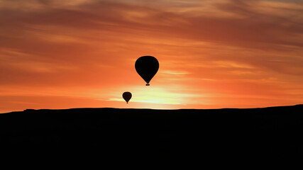 Cappadocia, Turkey - August 2017: Silhouettes of hot air balloons flying in Cappadocia landscape with dramatic morning sky, Turkey