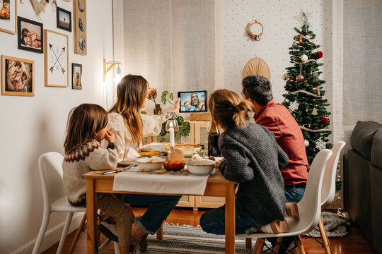 Family doing a videocall during vegetarian christmas dinner in a cozy living room