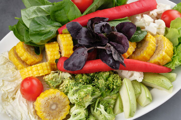 Plate of fresh chopped vegetables and herbs for hot-pot cooking. Chinese cuisine. View from above.