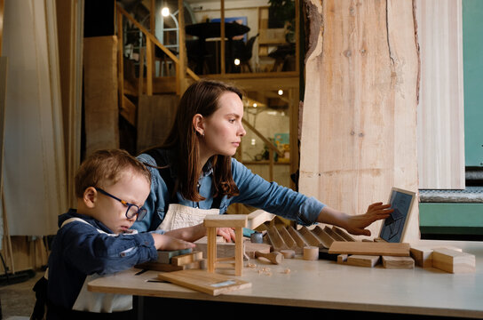 Little boy with mom making wooden toy in workplace