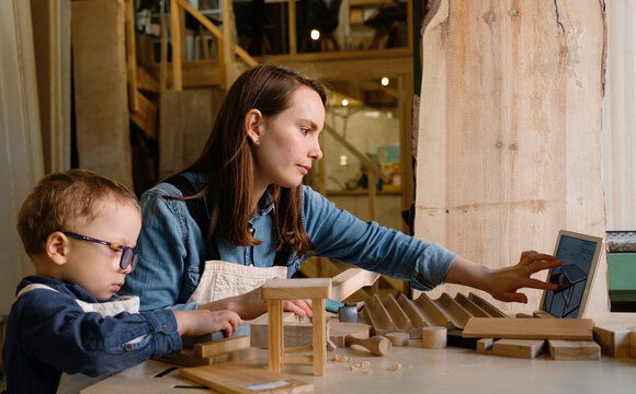 Woman with little kid assembling toy table in workshop