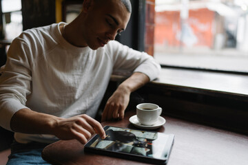 Young Man Using Computer Seated in a Coffee Shop