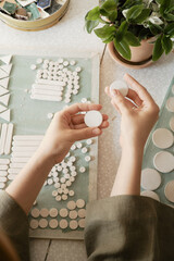 Girl is preparing to create ceramic jewelry from blanks. View from above.