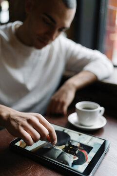 Young Man Using Computer Seated in a Coffee Shop