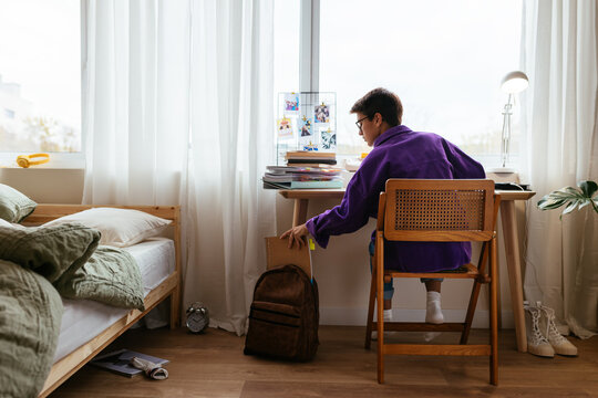 Girl In Messy Bedroom Busy With Homework