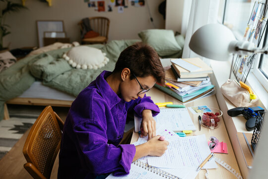 Smart teenager studying in messy bedroom