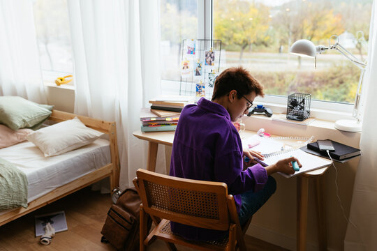 Teen kid studying at desktop in bedroom