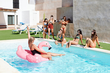 Women taking photos of their friend on a pool float