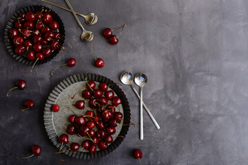 Creative mockup of cherries on metal plates on a dark gray background. Flat lay, copy space