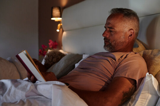 Mature man reading in bed at night