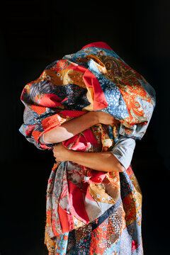 Woman holds a patchwork bedspread.