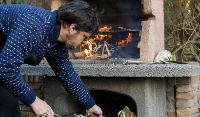 Close-up of a young man catching firewood to put on the barbecue