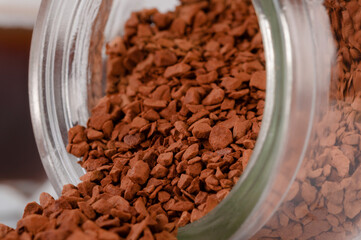 Instant coffee granules lying on the surface. Kofk granules spilled out of the jar lying on the table.