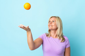 Middle age Lithuanian woman isolated on blue background holding an orange