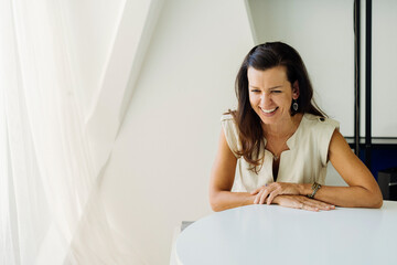 Cheerful woman sitting at table in light room