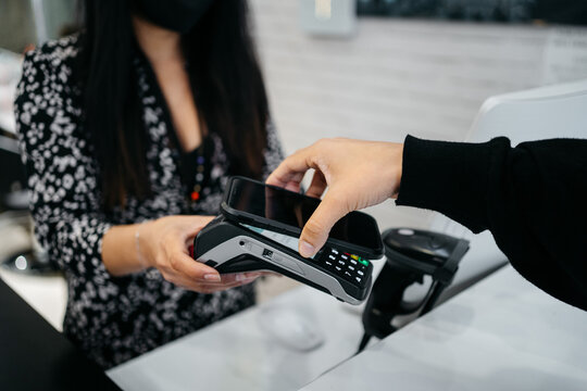 Anonymous woman contacless paying with her smartphone in a hairdresser 