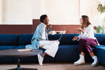 Happy diverse coworkers talking on sofa