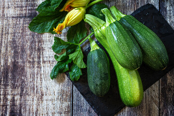 Harvesting zucchini. Healthy uncooked fresh green zucchini on a wooden kitchen table. Top view flat lay background. Copy space.