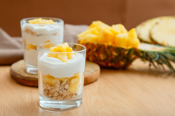 Tasty pineapple desserts with chopped fresh juicy pineapple. Breakfast dessert with oat granola,...