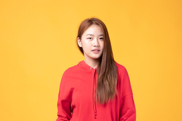 Portrait of beautiful young Asian girl model long hair in red coat summer clothes feeling smile, happy and enjoying in studio isolated on yellow background.