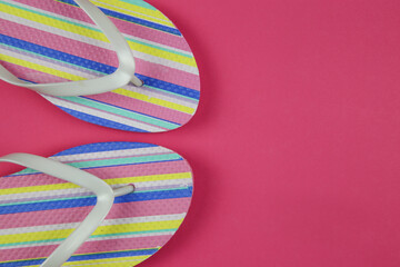 Top view on isolated colorful striped pair flip flops on pink background with copy space