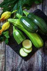 Harvesting zucchini. Healthy uncooked fresh green zucchini with slice on a wooden kitchen table. Top view flat lay background. Copy space.