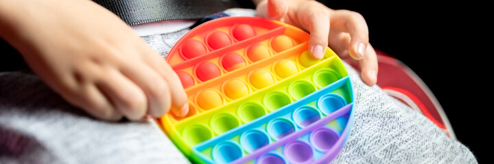 anti stress sensory pop it toys in a children's hands. a little happy kid boy plays with a simple...