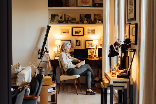 Middle Aged Woman Reading Book At Home