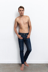 Photo of handsome man guy topless naked torso metrosexual hot tender body holding hands in pockets looking side attentively wear jeans isolated white background.