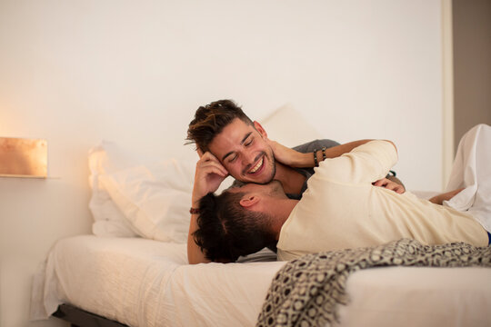 Young man kissing boyfriend on bed at home