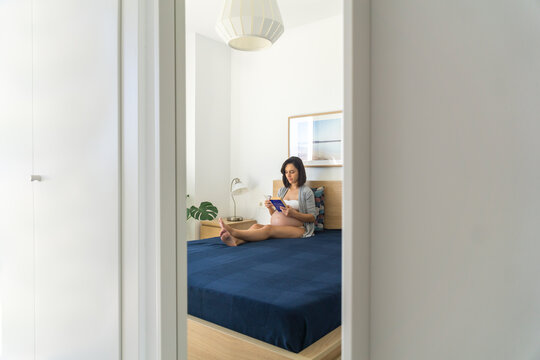 Pregnant young woman reading a book in the mirror at home