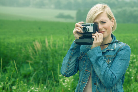 Portrait of beautiful blonde female photojournalist traveling and taking picture outdoors