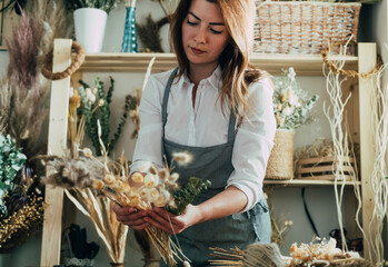 Beautiful Florist Arranging Bouquet of a Dry Flowers at her Flower Shop.
Young talented woman...