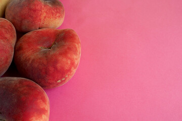 close several pink peach figs lie on the left on a pink background. view from above. artificially...