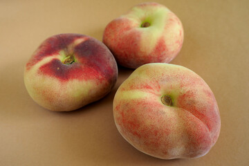 close up three pink peach figs lie on a brown background. side view. artificially obtained fruits rich in vitamins